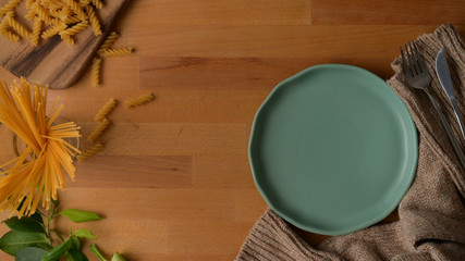 Top view of dinning table with mock up plate, silverware on tablecloth, copy space and ingredients decorated