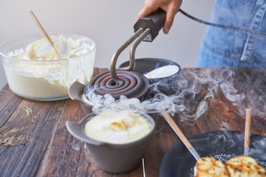 Crop view of anonymous woman burning delicious creme brulee with iron cast grill