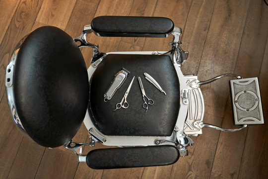 Top view of set of various hairdressing instruments including scissors trimmer and razor placed on chair in barbershop