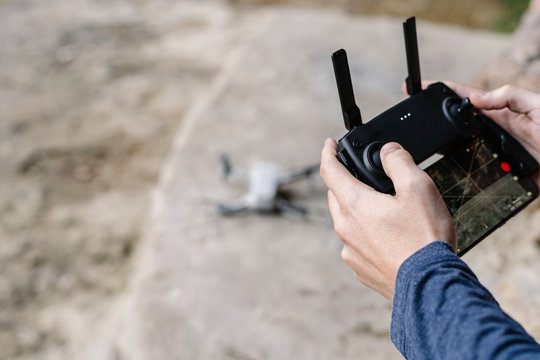 Unrecognizable crop person controlling unmanned drone remotely with professional equipment in mountainous area