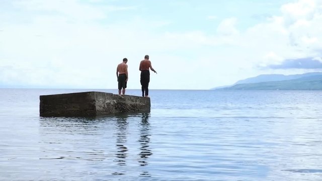 Two men jump into the water at the same time.