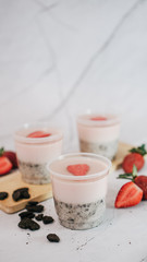 Strawberry Oreo layered pudding in cup with fresh strawberries on a wooden plate