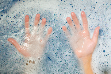 the hands of a child in the blue water of the pool