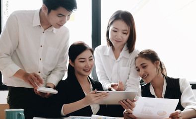 Asian business searching information for provide ideas in new startup project using touch pad during brainstorming, collaboration and cooperation.Four colleagues sharing opinions at meeting