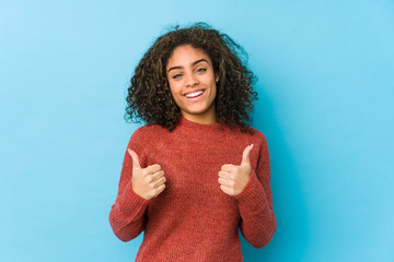 Young african american curly hair woman raising both thumbs up, smiling and confident.
