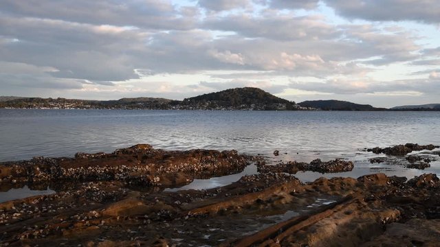 Clouds in the late afternoon over the water and rocky oyster covered foreshore