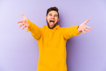 Fototapeta premium Young man isolated on purple background feels confident giving a hug to the camera.