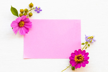 Naklejka na ściany i meble notepaper with pink flowers cosmos ,purple flowers arrnagement flat lay postcard style on background white wooden