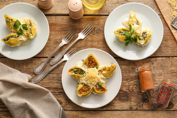Plates with tasty conchiglioni pasta on table