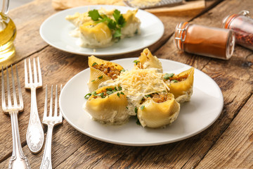 Plate with tasty conchiglioni pasta on table