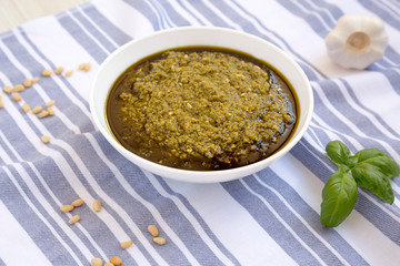 Homemade Basil Pesto with Parmesan and Pine Nuts on a white wooden background, side view.