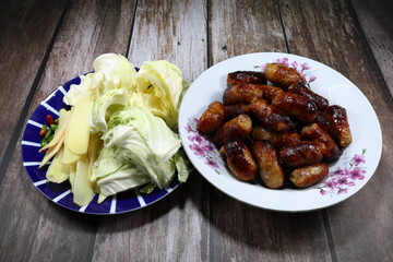 Famous traditional roasted pickled pork sausage and pile of fresh vegetable side dish. Popular party menu in Asia. 