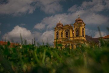 Saint George cathedral in the centre of Timisoara in Romania known also as the Dome on Plata Unirii on a warm summer day with blue skies and clouds. Grass in the foreground