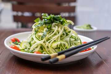 Noodles of spiralized zucchini, cucumber, cherry tomato, garlic in a creamy pesto from avocado. Raw food for vegetarian