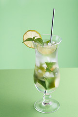 Minimalistic mojito cocktail on a green background with silver straw. Vertical photo with place for your text.