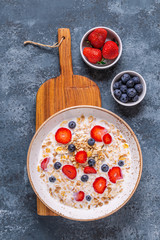 Healthy breakfast, bowl with oat granola, milk and berries.