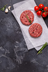 Fresh raw meat burger cutlet with herbs and spices on the black stone board