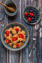 Trendy breakfast with mini pancakes, blueberries and strawberries