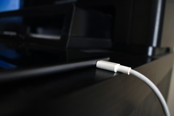 Charger with tablet on the table.  Selective focus on the USB cable that plugging to the tablet. 