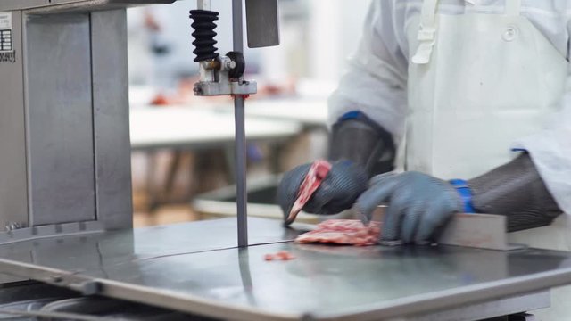 Meat processing plant, butcher cuts pork carcasses, meat production and food industry, the process of harvesting meat, butcher cuts the meat into pieces.