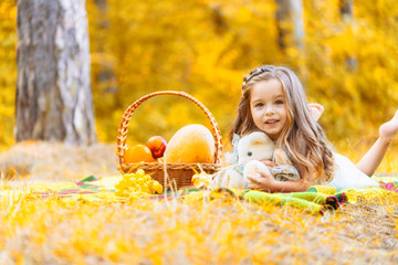 Weekend at picnic. Lovely caucasian girl on grass meadow with basket full of fruits. Female child kid on nature sit on white blanket having fun. Sunny summer Beautiful fall day.