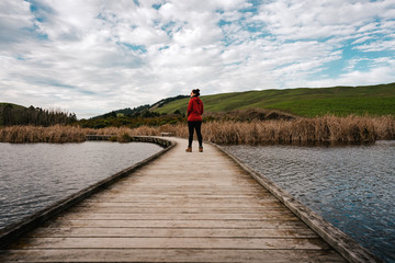 Woman walking on wooden walkway on Peka Peka Wetlands, Hawke's Bay, New Zealand.