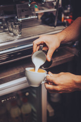 Fototapeta na wymiar Man making an cappuccino by pouring fresh foam milk