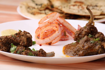 Bhuna Gosht Mutton masala OR Indian Lamb masala and mutton curry Served with naan or bread and onion over wodden background.