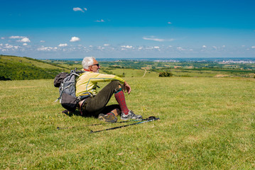 Fototapeta na wymiar Caucasian senior man hiker taking a break in nature overlooking the beautiful nature landscape in the background