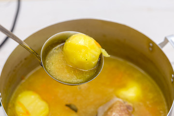 hand pours chicken soup on a white table