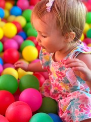 Fototapeta na wymiar cutie little baby girl having fun in the ball pool
