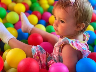 Fototapeta na wymiar pretty little baby girl having fun in the ball pool