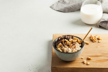 Oatmeal porridge with nuts, chocolate in a gray bowl, a glass of milk. Breakfast, healthy food.Copy space. Good morning.