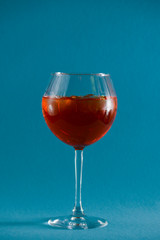 Red tropical alcohol cocktail with ice. Isolated on pastel blue background with copy space. Fruit cocktail in wine glass