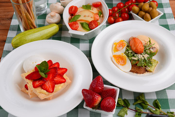 Meat with boiled eggs, lasagna, puff pastry strawberry dessert served on the table. Italian cousine concept.