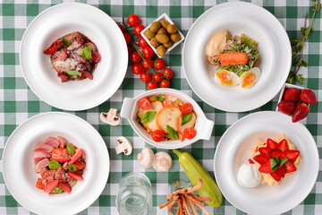 Meat with boiled eggs, lasagna, puff pastry strawberry dessert served on the table. Italian cousine concept.