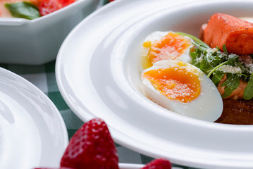Nutritious meat salad with boiled egg slices, close up. Served in a white plate.