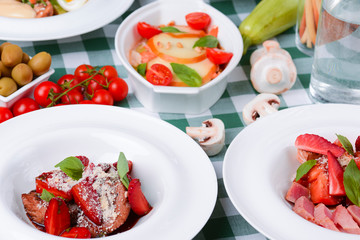 Meat with boiled eggs, lasagna, puff pastry strawberry dessert served on the table. Italian cousine concept.