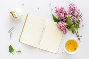 Lilas flowers bouquet with cup tea and notepad top view