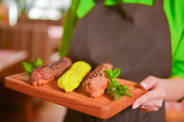 Close up of waitress serving traditional french dessert. Eclair with chocolate icing. Restaurant service.