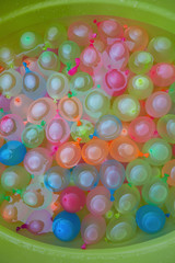 many colorful water balloons in a plastic basin