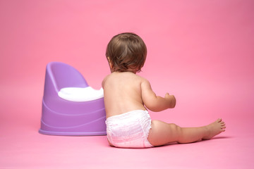 Cute baby in a diaper sitting on a potty. Toilet and potty training.