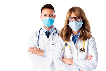 Shot of male and female doctors wearing face mask while standing together at isolated white...