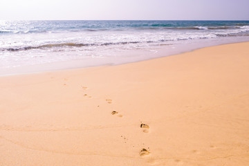Human footprints leading away from the viewer into the sea. Empty beach, tourism concept, travelling.