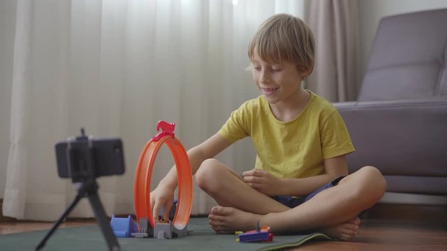 A little boy plays and talks with his friends and relatives through a video-call using a smartphone. He stays in quarantine, because of the Covid-19 danger. Concept of the second wave of COVID