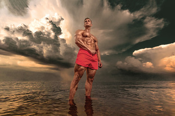 Fit athlete bodybuilder in the sea. Attractive young man lifeguard.