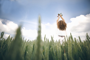 A Young Beautiful Girl With Red Rose In Hands Standing Back Against Blue Sky