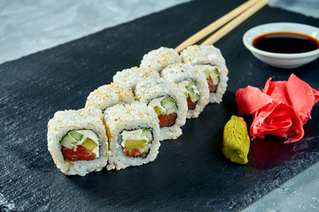 Sushi roll california in sesame with avocado, tuna and philadelphia cheese on a black slate board. Selective focus