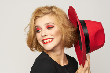 Cute blonde short haired red hat in hand close-up light background