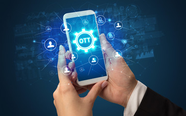 Female hand holding smartphone with OTT abbreviation, modern technology concept